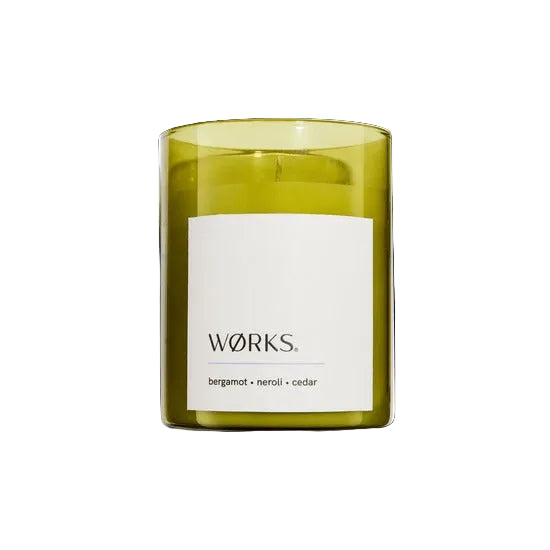 Green candle with a white label on a white background works bergamot cedar